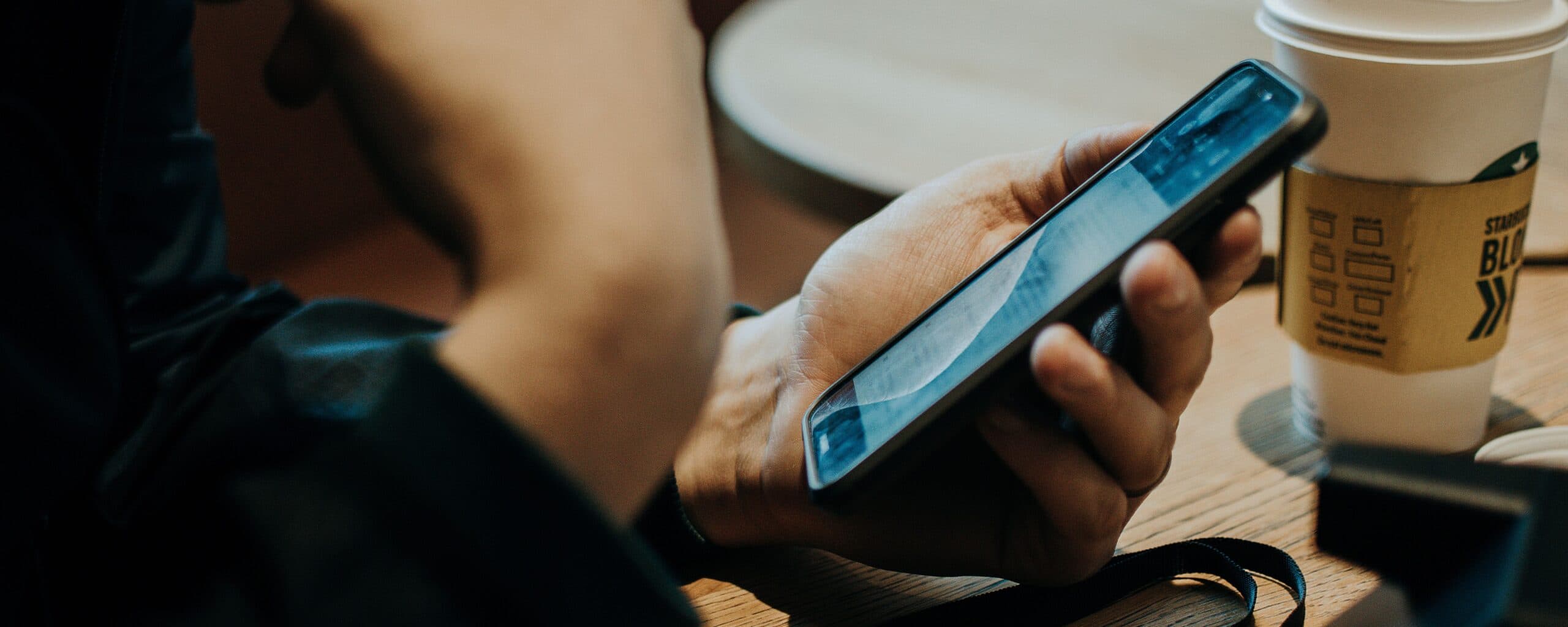 person holding phone in a coffee shop
